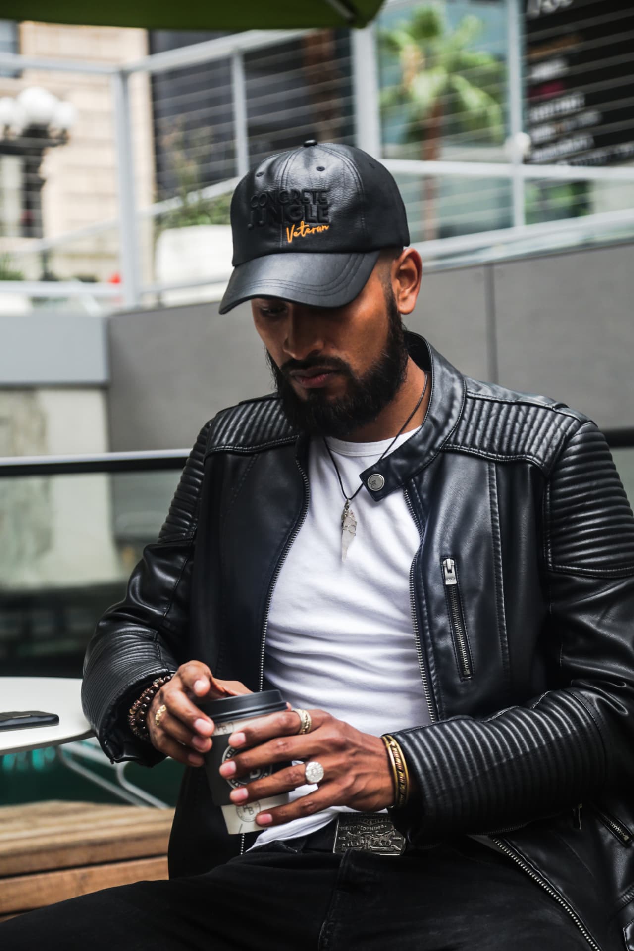 Closing image — leather cap and jacket photographed at an outdoor cafe