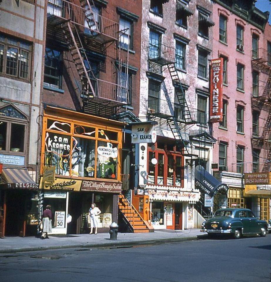 An earlier Greenwich Village streetscape: hand-painted shop signs, fire escapes and a parked sedan.