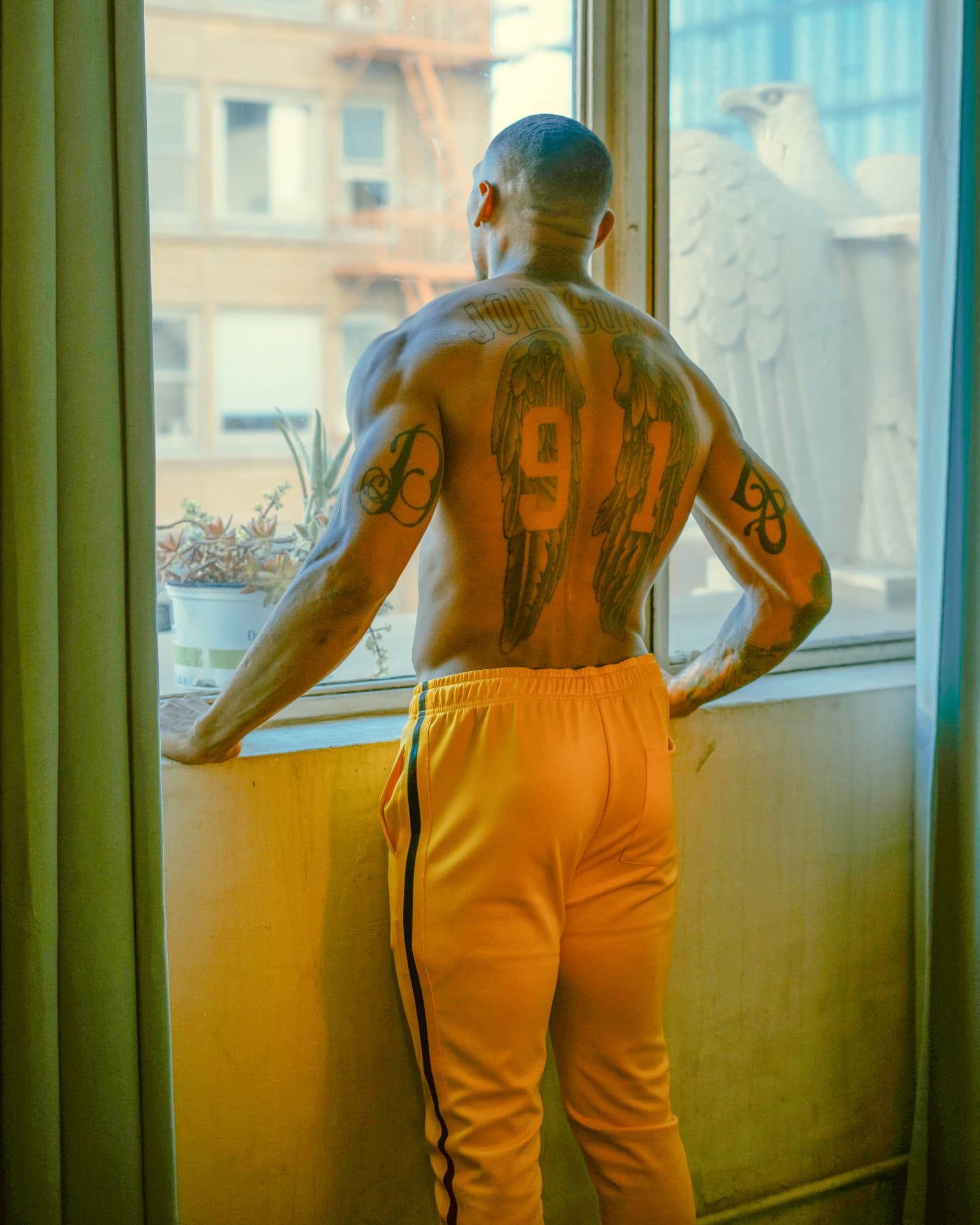 Yellow side-stripe track pants photographed at a loft window