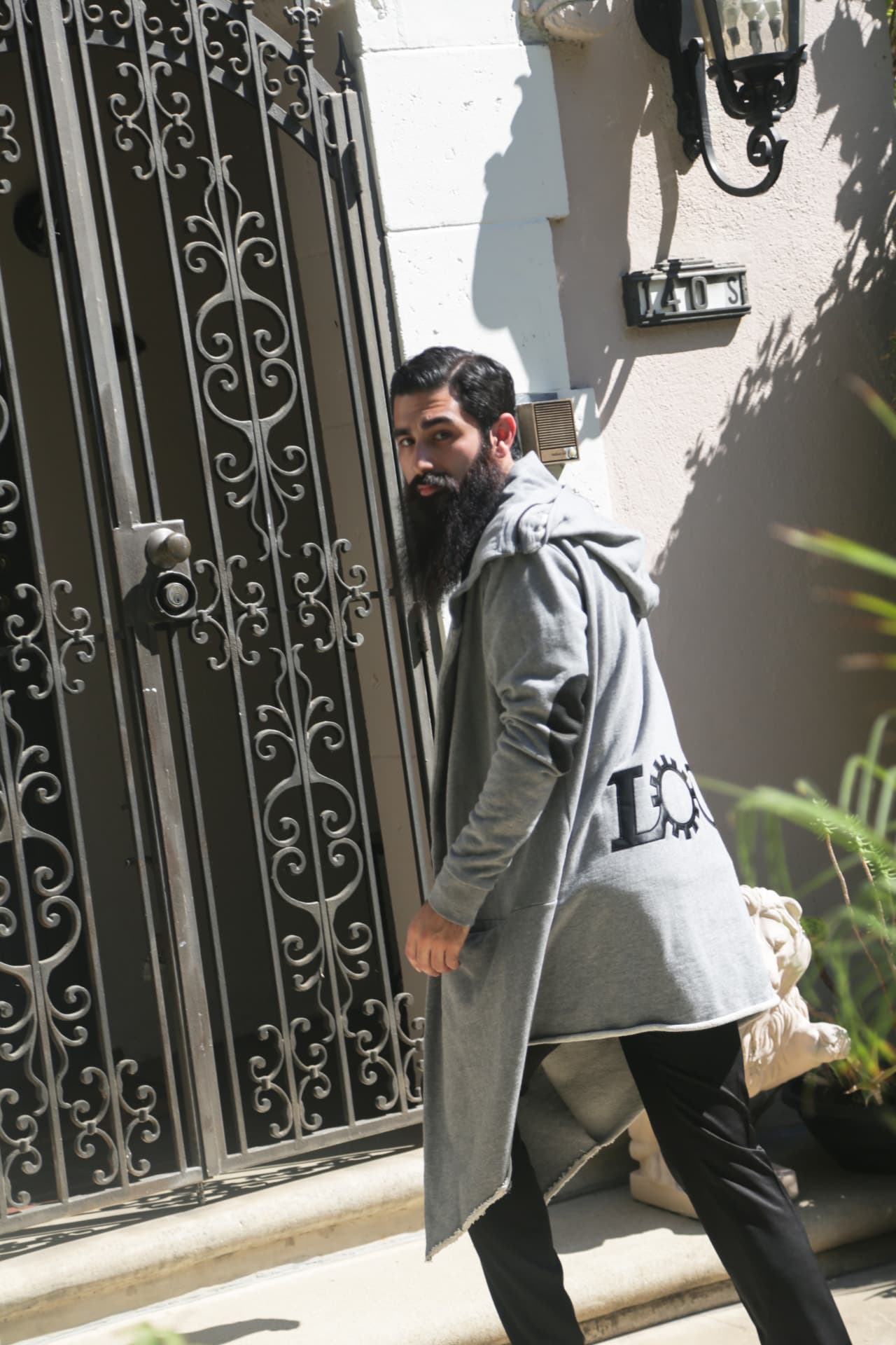 Grey longline hooded cardigan photographed at a wrought-iron gate