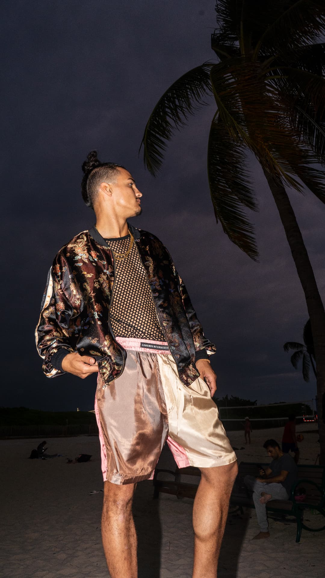 Brocade bomber and satin shorts photographed on the beach at night