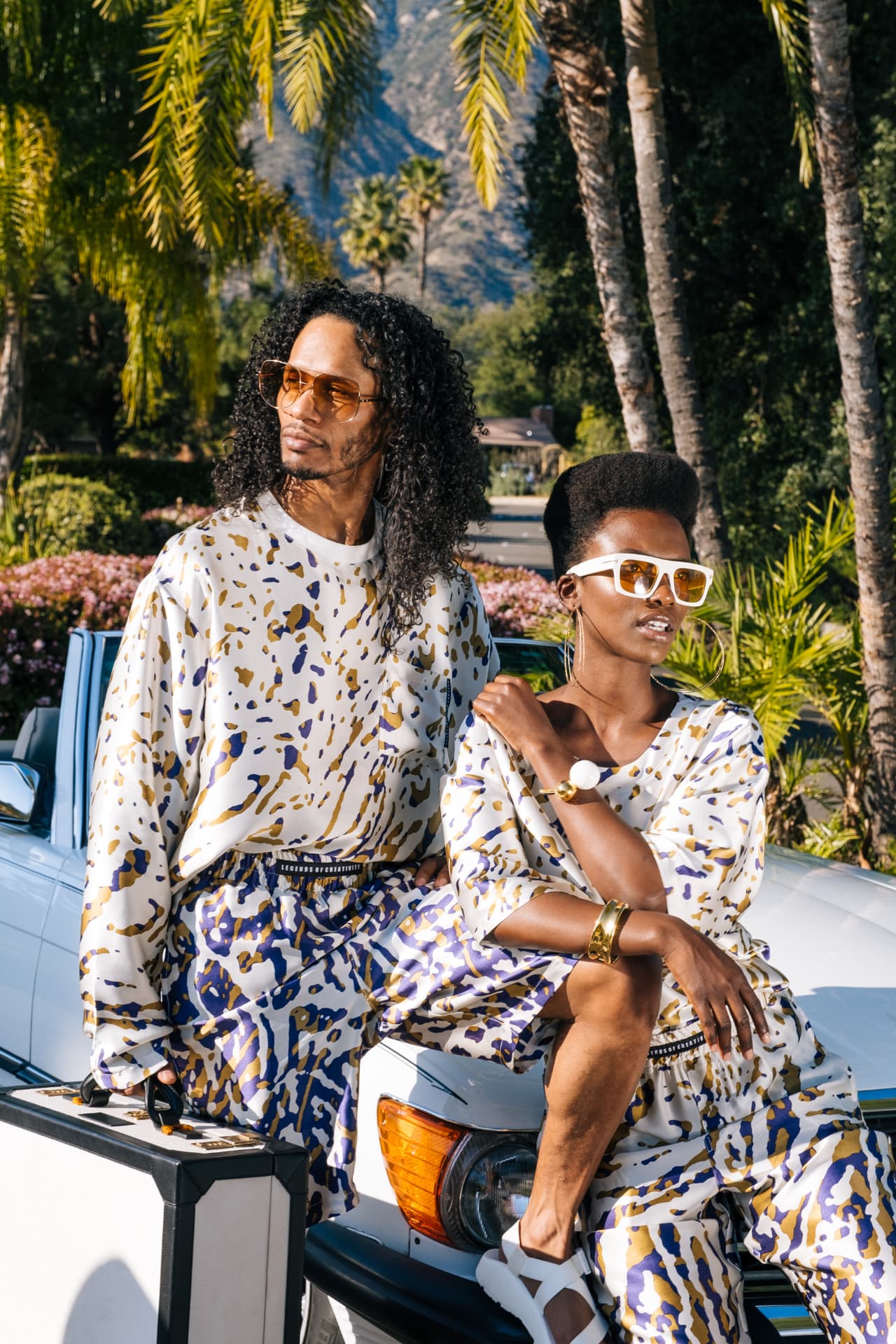 Wanderlust opening image — matching splash-print sets on a vintage white Mercedes convertible