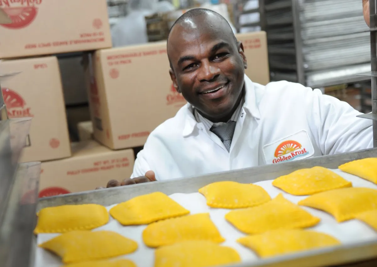 Golden Krust founder holding a tray of freshly baked Caribbean patties.