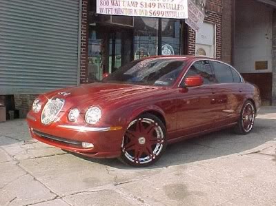 A deep-red custom Jaguar sedan on custom rims parked outside the Bronx store.