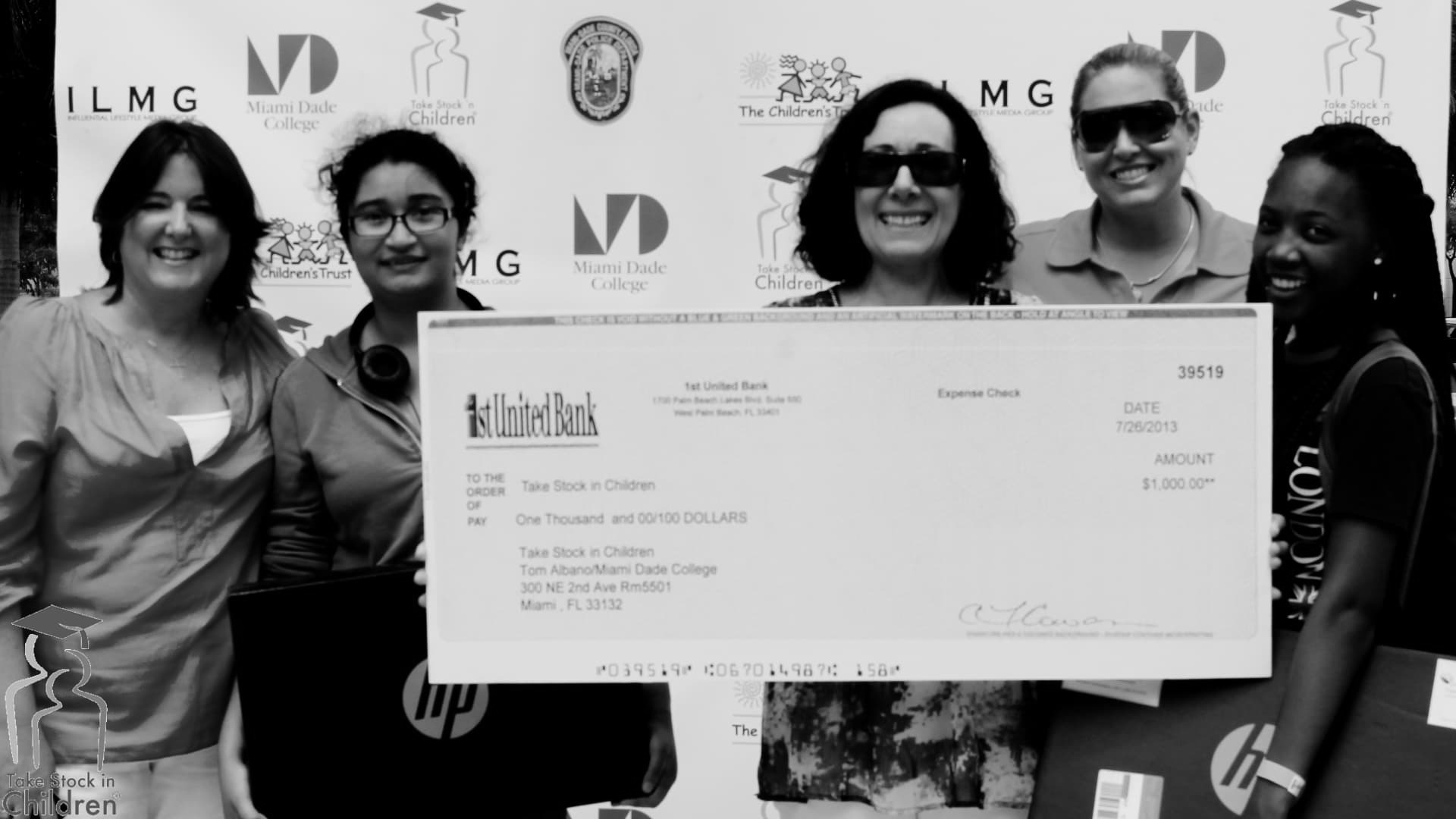 Volunteers and staff holding a ceremonial check presented to Take Stock in Children at the Miami-Dade College outreach event.