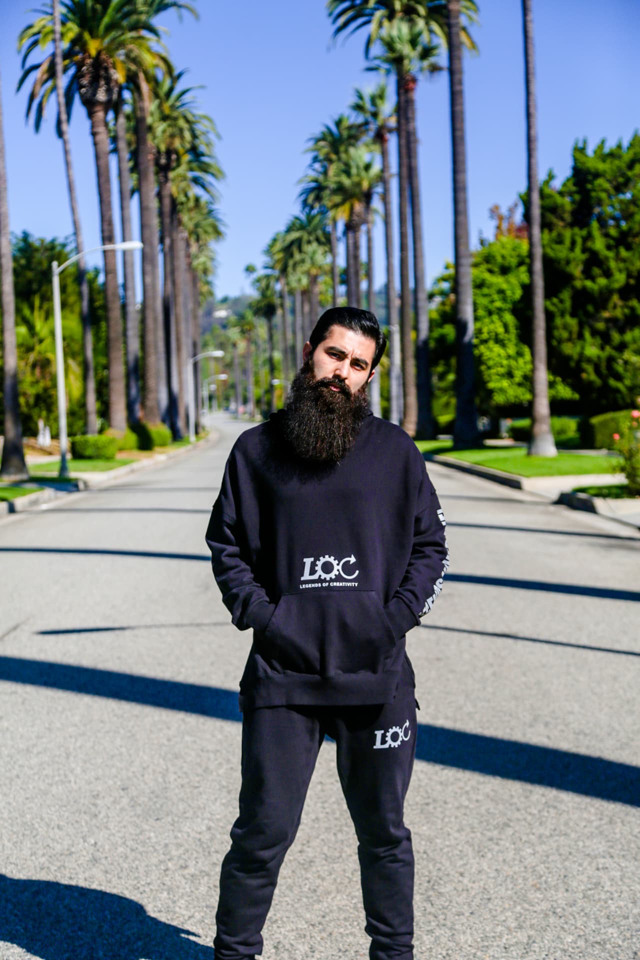 Black logo hoodie and joggers photographed on a palm-lined street