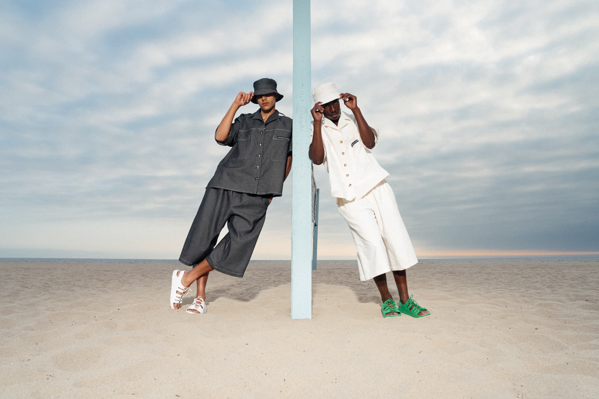 Two looks in denim and off-white sets photographed against a beach volleyball post
