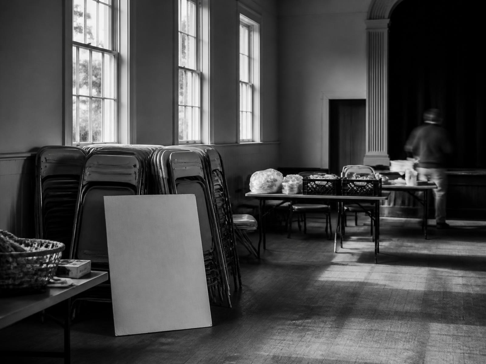A community hall being set up before an event, chairs stacked and tables laid out