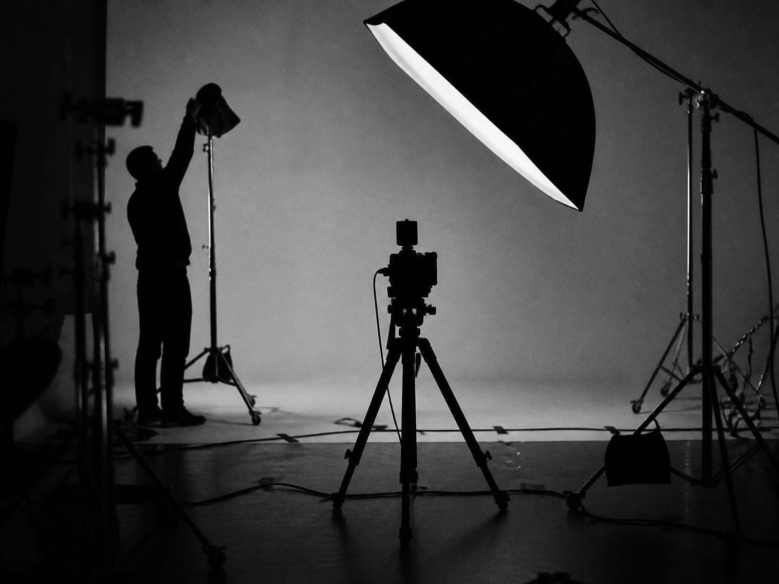 A photography set mid-build: lights, stands and a camera facing a seamless backdrop