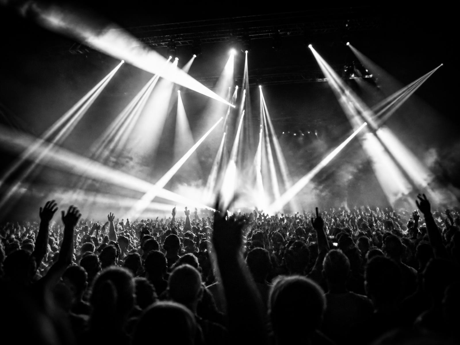 Stage lighting cutting through haze above an audience at a live event