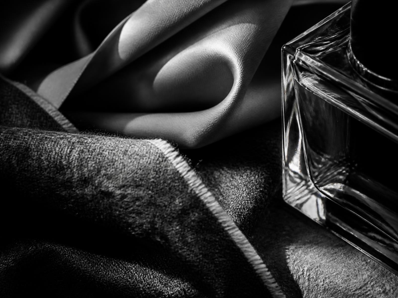 Close study of silk, wool and a glass bottle under raking studio light